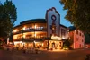 Collective enquiry Illuminated hotel building with balconies and outdoor seating in the evening