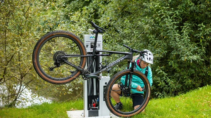 Person repairing mountain bike at an outdoor public bike repair station