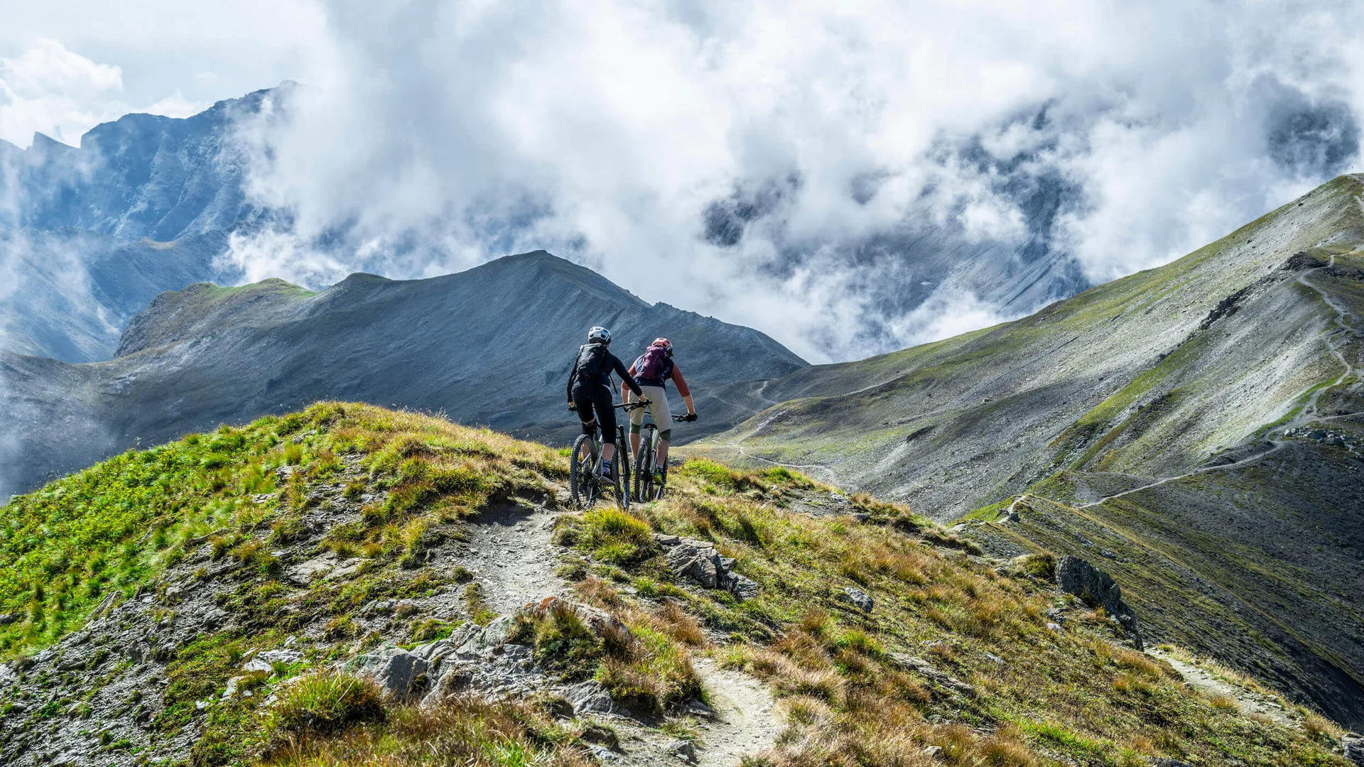 Zwei Mountainbiker fahren auf einem Bergpfad mit Nebelschwaden