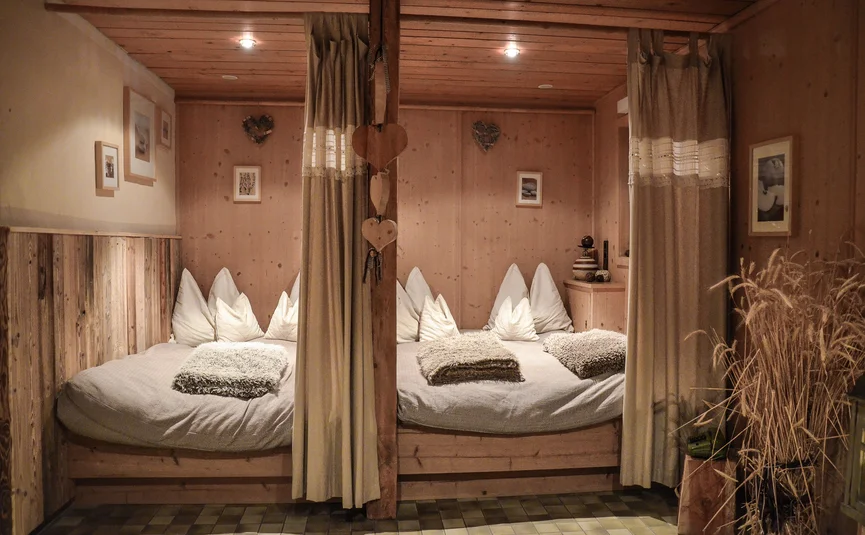 Gemütliche Holzbett-Nische mit weißen Kissen und Vorhängen in rustikalem Zimmer