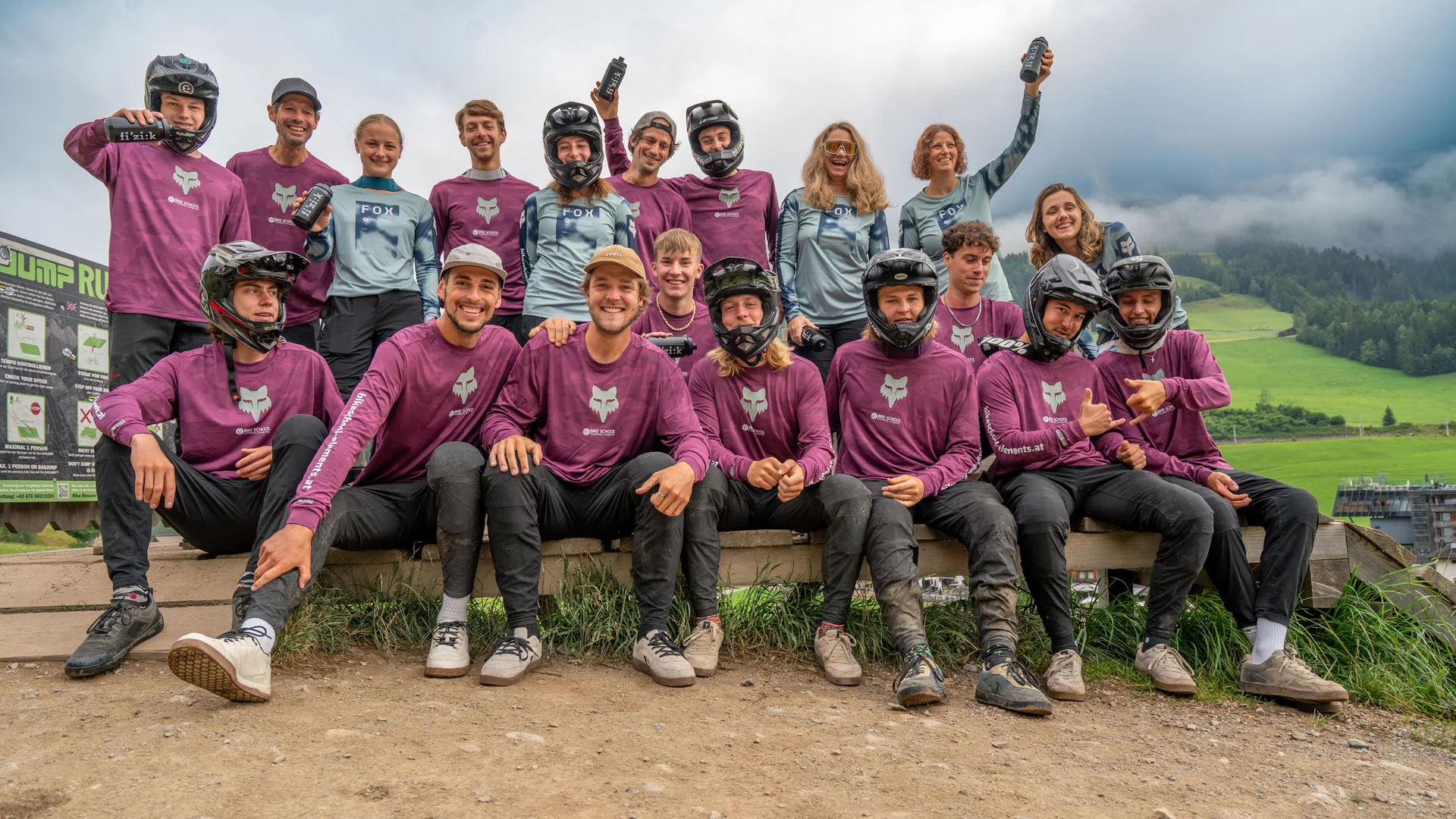 Gruppenfoto von Mountainbikern in Schutzkleidung und Trikots in einer Berglandschaft