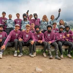 Gruppenfoto von Mountainbikern in Schutzkleidung und Trikots in einer Berglandschaft