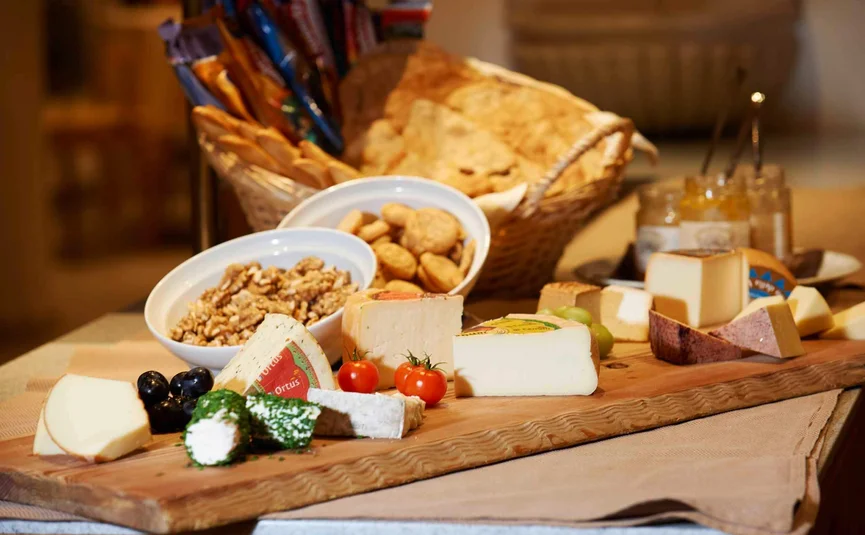 Houten plank met verschillende kazen, noten, brood en cherrytomaten