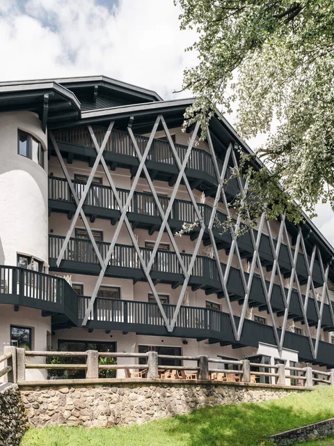 Modernes mehrstöckiges Gebäude mit Balkonen und Holzgitterstruktur in grüner Landschaft