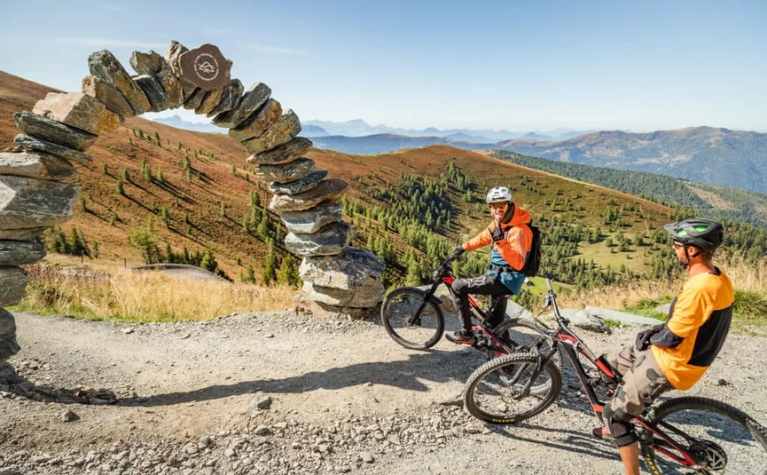 Flow Trail Special / 3 nights Two mountain bikers near a stone arch in the mountains on a clear day