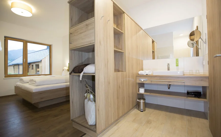 Modernes Hotelzimmer mit Bett, Schrank und Waschbeckenbereich