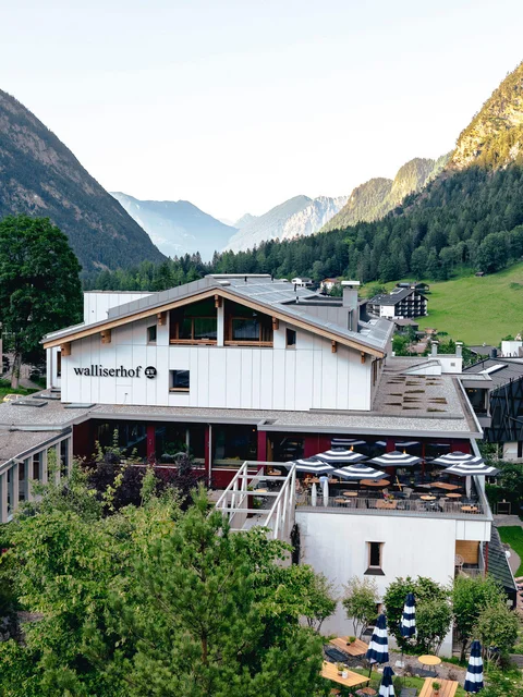 Hotel Walliserhof in einem Bergtal mit Terrasse und Sonnenliegen