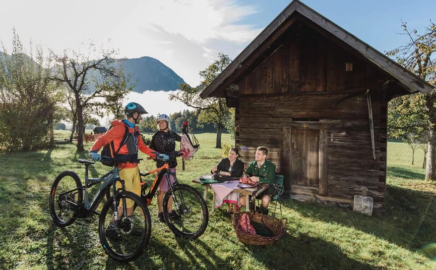 Twee fietsers praten met twee mensen buiten een houten hut