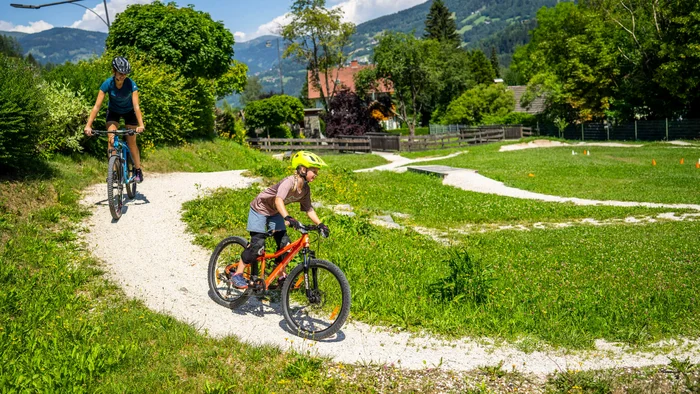 Children riding mountain bikes on a sunny forest trail in the mountains
