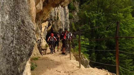 Fietsers op smal rotsachtig pad met beveiligingskabel en bos op de achtergrond