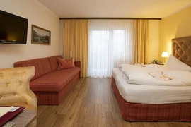 Cozy hotel room with double bed, sofa, and TV