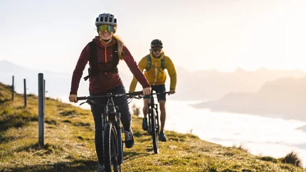 Zwei Personen fahren Mountainbike auf Bergweg bei Sonnenlicht