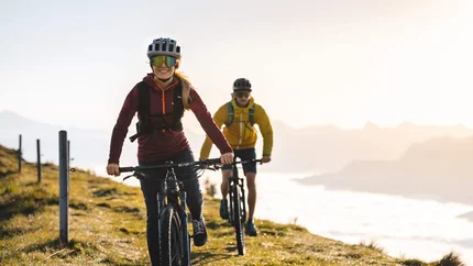 Zwei Personen fahren Mountainbike auf Bergweg bei Sonnenlicht