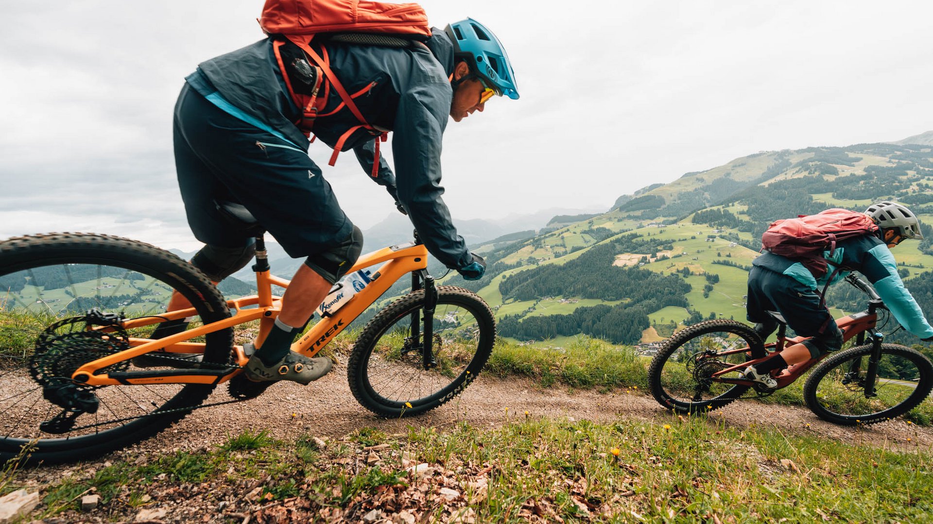 Zwei Mountainbiker fahren einen Bergpfad mit grüner Landschaft