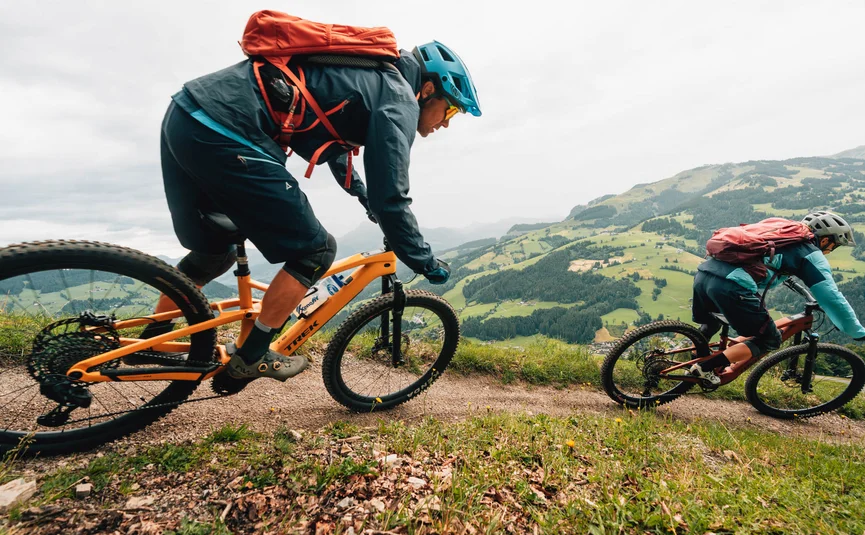 Zwei Mountainbiker fahren einen Bergpfad mit grüner Landschaft