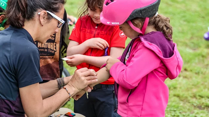 Frau klebt Pflaster auf den Arm eines Mädchens mit Fahrradhelm