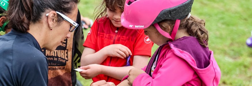 Frau klebt Pflaster auf den Arm eines Mädchens mit Fahrradhelm