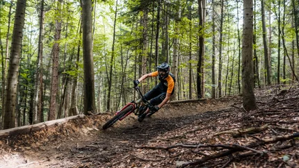 Mountainbiker fährt schnell auf Waldweg um Kurve