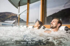 Bike & Wellness - 3 nights Couple relaxing in a hot tub with mountain view