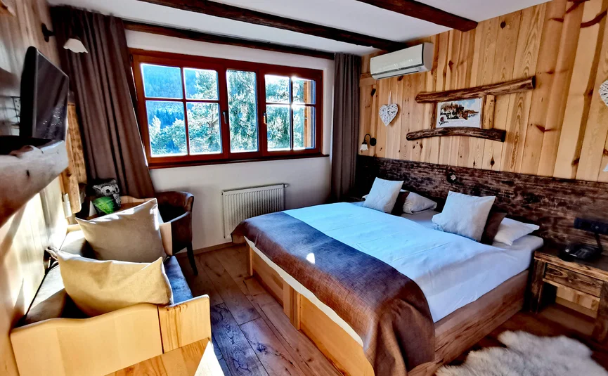Gemütliches Schlafzimmer mit Holzmöbeln, großem Bett und Fenster mit Alpenblick