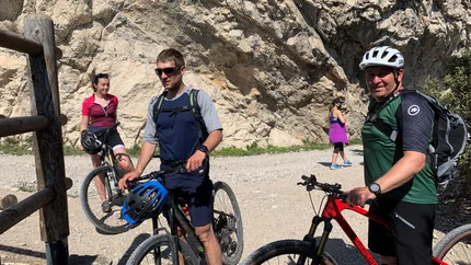 Vier Radfahrer mit Mountainbikes vor felsiger Bergwand auf Wanderweg