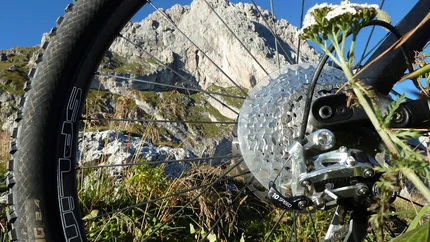 Achterwiel van mountainbike met berg en blauwe lucht op de achtergrond