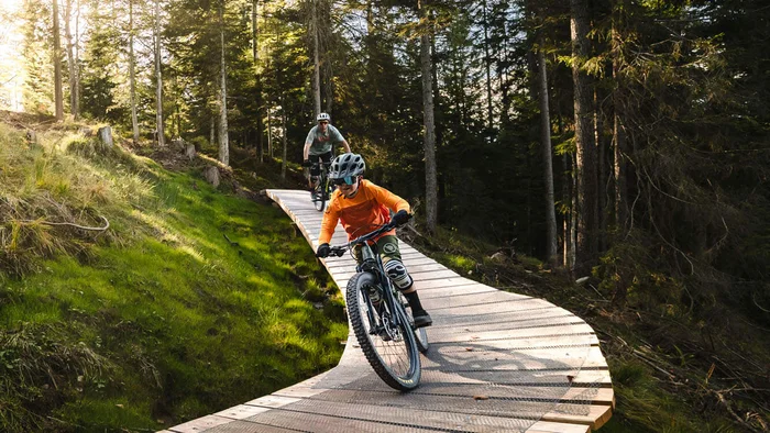 BEST OF Familien-Bikeurlaub © Klaus Listl Zwei Mountainbiker auf einem Holzsteg in einem sonnigen Wald