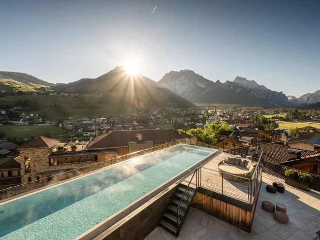 Rooftop infinity pool with mountain view at sunset