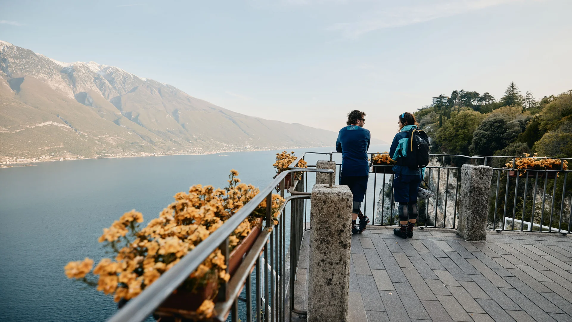 Zwei Menschen auf Aussichtspunkt mit Blick auf See und Berge
