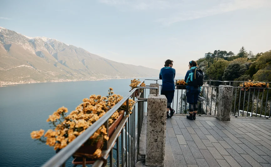 Zwei Menschen auf Aussichtspunkt mit Blick auf See und Berge