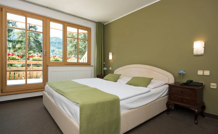 Gemütliches Schlafzimmer mit grünem Akzent und Blick auf Natur vom Fenster