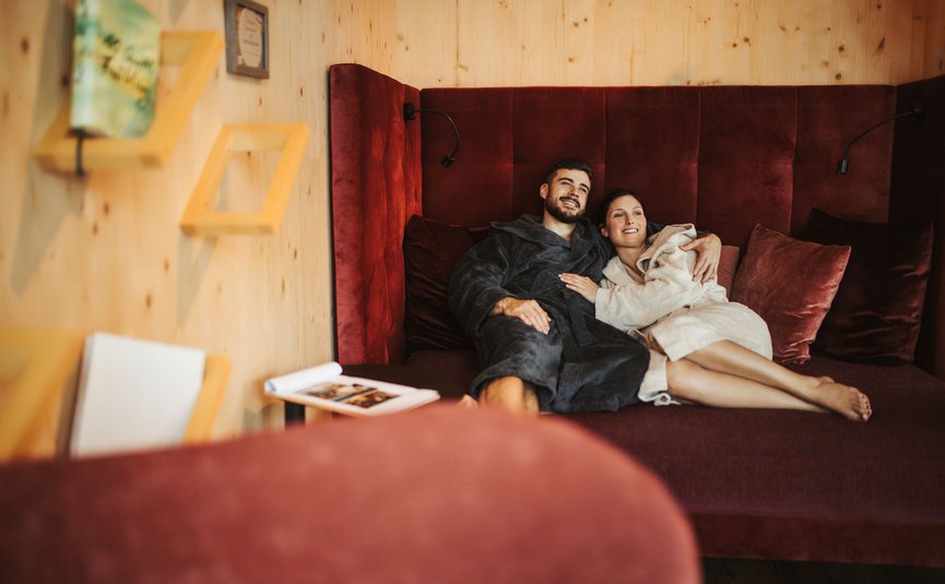 See-Aktivhotel Regitnig - Hotel & Chalets **** © Daniel Waschnig Paar entspannt auf gemütlichem Sofa in Holzraum
