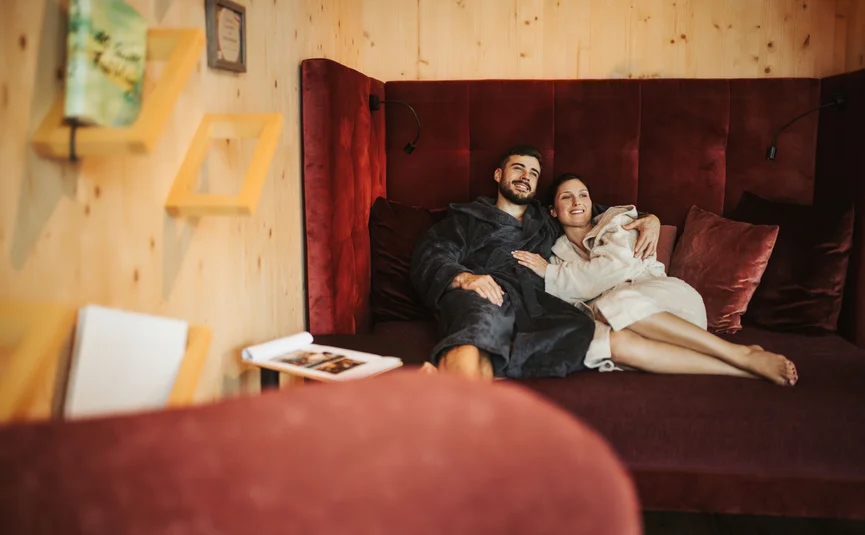 Paar entspannt auf gemütlichem Sofa in Holzraum