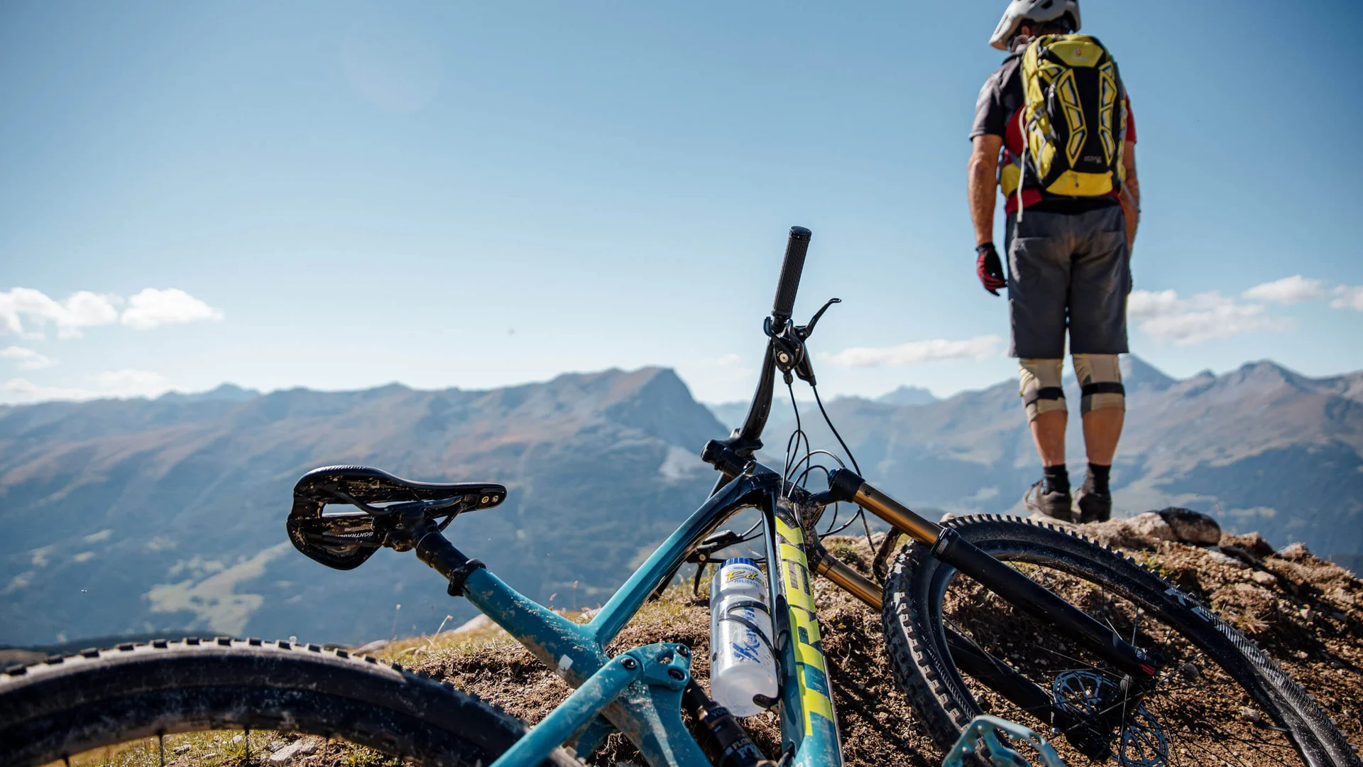 Mountainbike liegt auf Berggipfel, Radfahrer schaut auf Berge