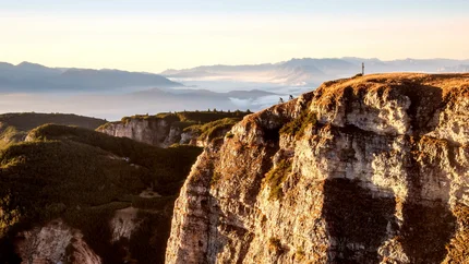 Two cyclists riding along a cliff with a mountainous landscape