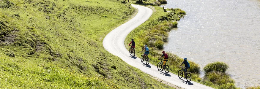 Hotel Rupertus: Ein Retreat für Yogis und Biker © Saalfelden Leogang Touristik Vier Radfahrer auf einem Weg entlang eines Sees in hügeliger Landschaft