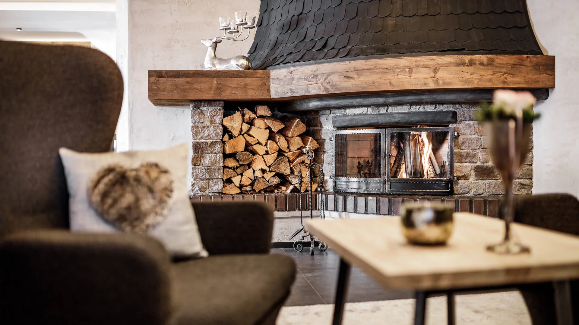 Gemütlicher Raum mit Kamin, Feuerholzstapel und braunem Sessel