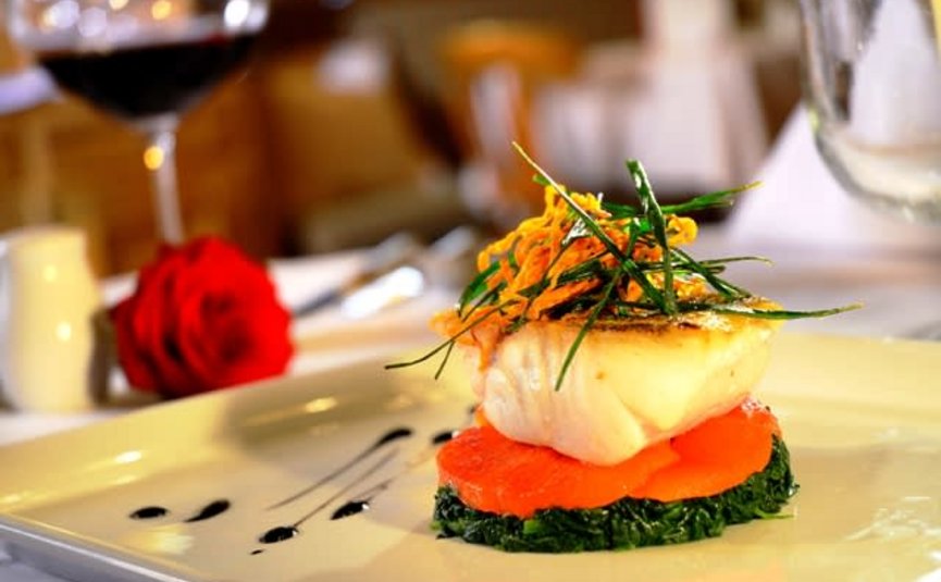 Elegant visgerecht met groenten en rode wijn in een restaurant