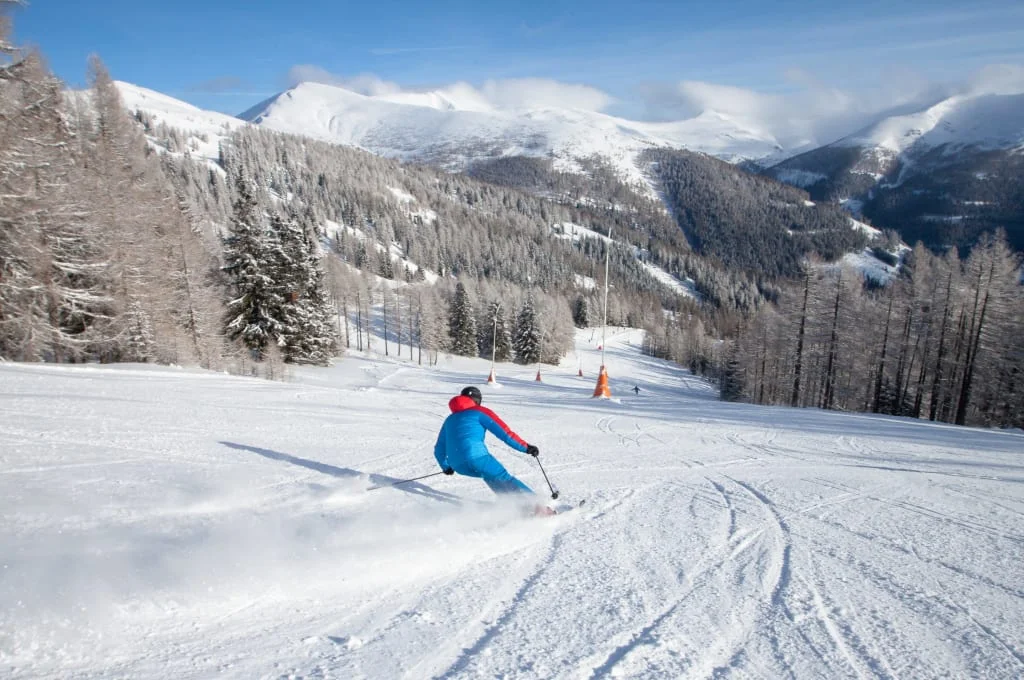 Ski & Wellness / 4 Nächte Skifahrer in blauer Jacke fährt auf verschneiter Piste in Berglandschaft