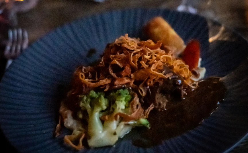 Gedeckter Tisch mit Teller voller Essen und Weinglas in gemütlicher Atmosphäre