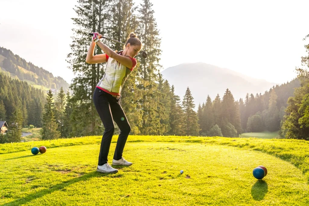 Stay here - Free golf / 3 Nächte Vrouw speelt golf op groene baan met bergen en bomen op de achtergrond