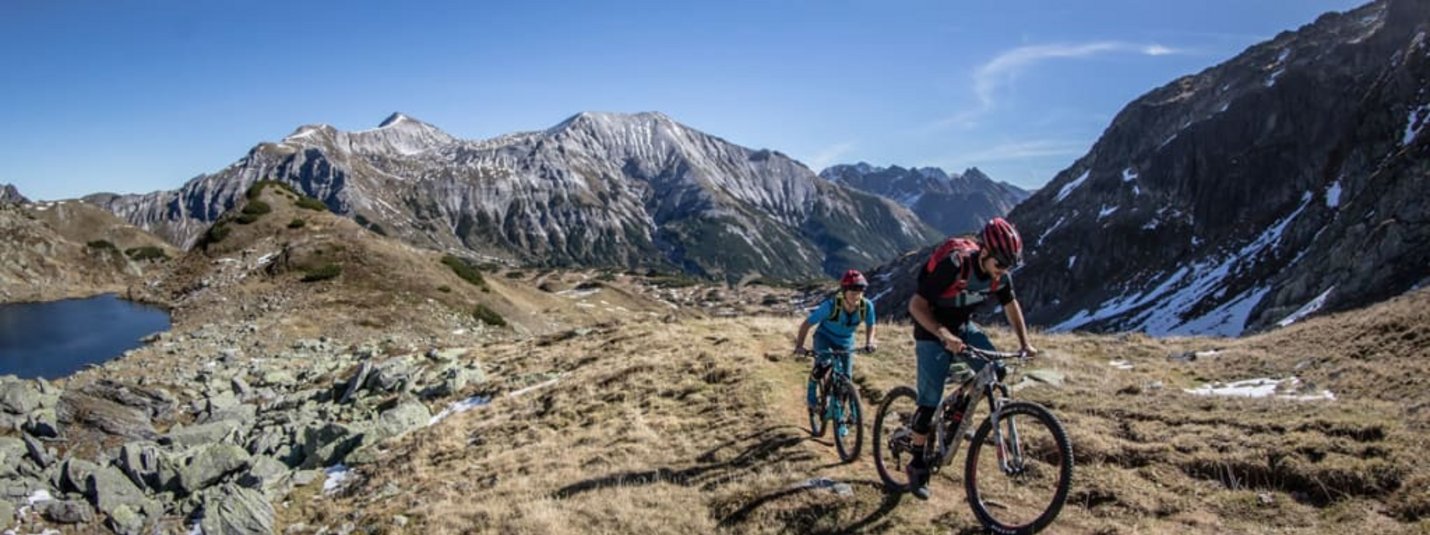 Zwei Mountainbiker fahren auf einem Bergpfad bei sonnigem Wetter