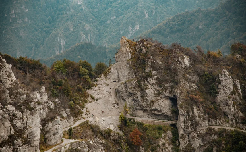 Cyclists on a mountain forest path with rocks and caves