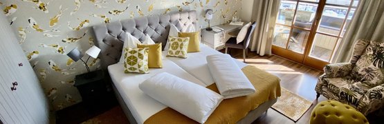 Gemütliches Schlafzimmer mit gelb gemusterter Tapete und sonnigem Balkon