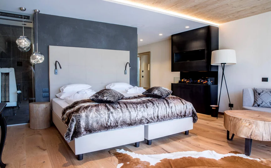 Modern bedroom with fireplace, wooden ceiling, and fur bedspread