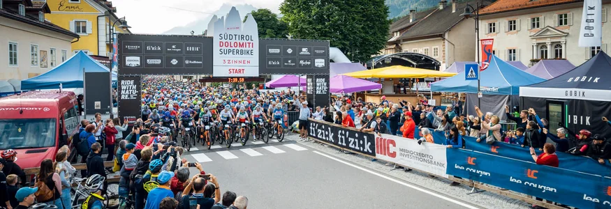 Start des Südtirol Dolomiti Superbike Rennens mit Radfahrern und Zuschauern