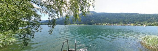 Bike & Hike mit Markus Rosenauer Blick auf einen See mit Pier und Bergen im Hintergrund an einem sonnigen Tag