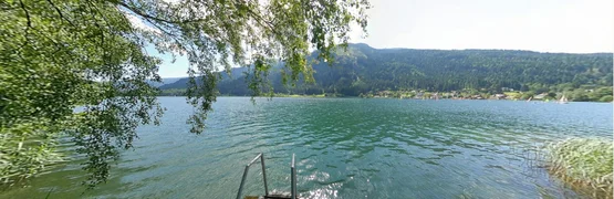 Uitzicht op een meer met een steiger en bergen op de achtergrond op een zonnige dag