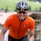 Cyclist in orange jersey and helmet smiling while cycling