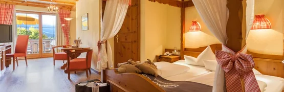 Gezellige hotelkamer met hemelbed, zithoek en balkon met uitzicht op de bergen